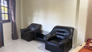 A room with two black leather chairs, a small table, and a window with curtains. - Southern Star Resort (Pattaya)