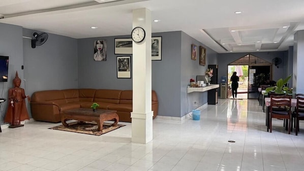A spacious living area with a brown sofa, a wooden coffee table, and a statue.