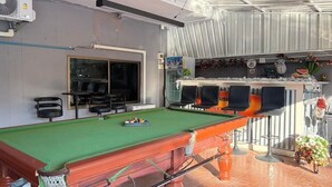 A pool table with chairs, a bar area with a 'WELCOME' sign, and a view of the outside. - Southern Star Resort (Pattaya)
