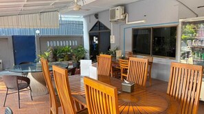 An outdoor seating area with wooden tables and chairs, a glass-top table, and potted plants. - Southern Star Resort (Pattaya)