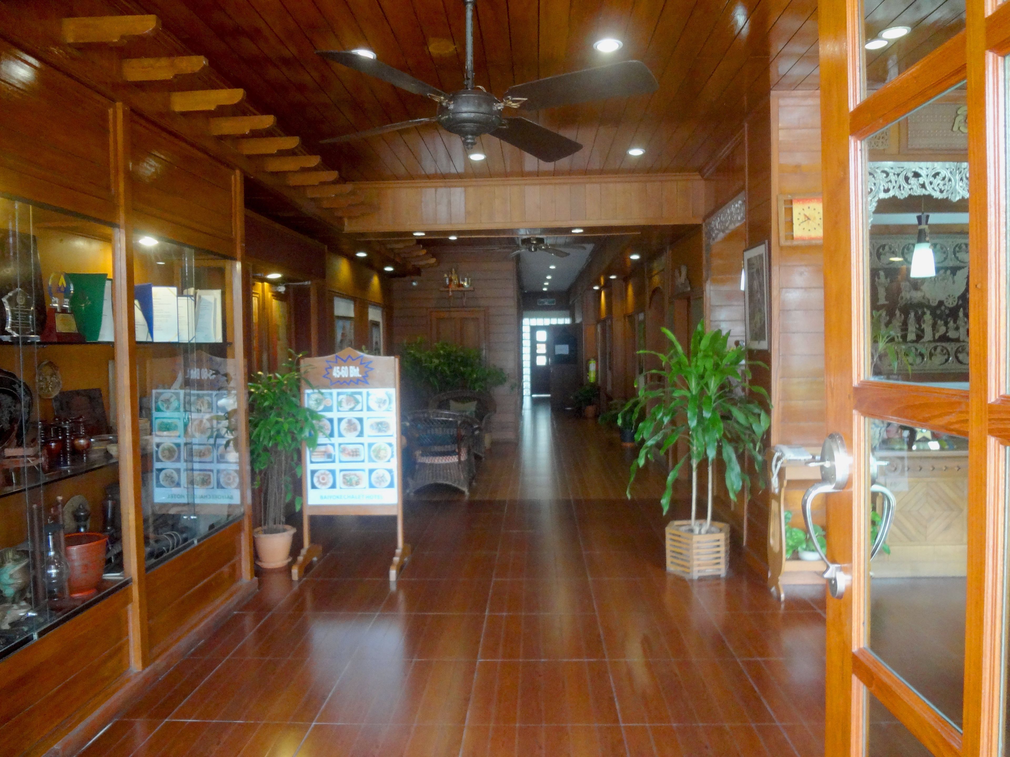 A hallway with wooden floors, ceiling fans, and potted plants.