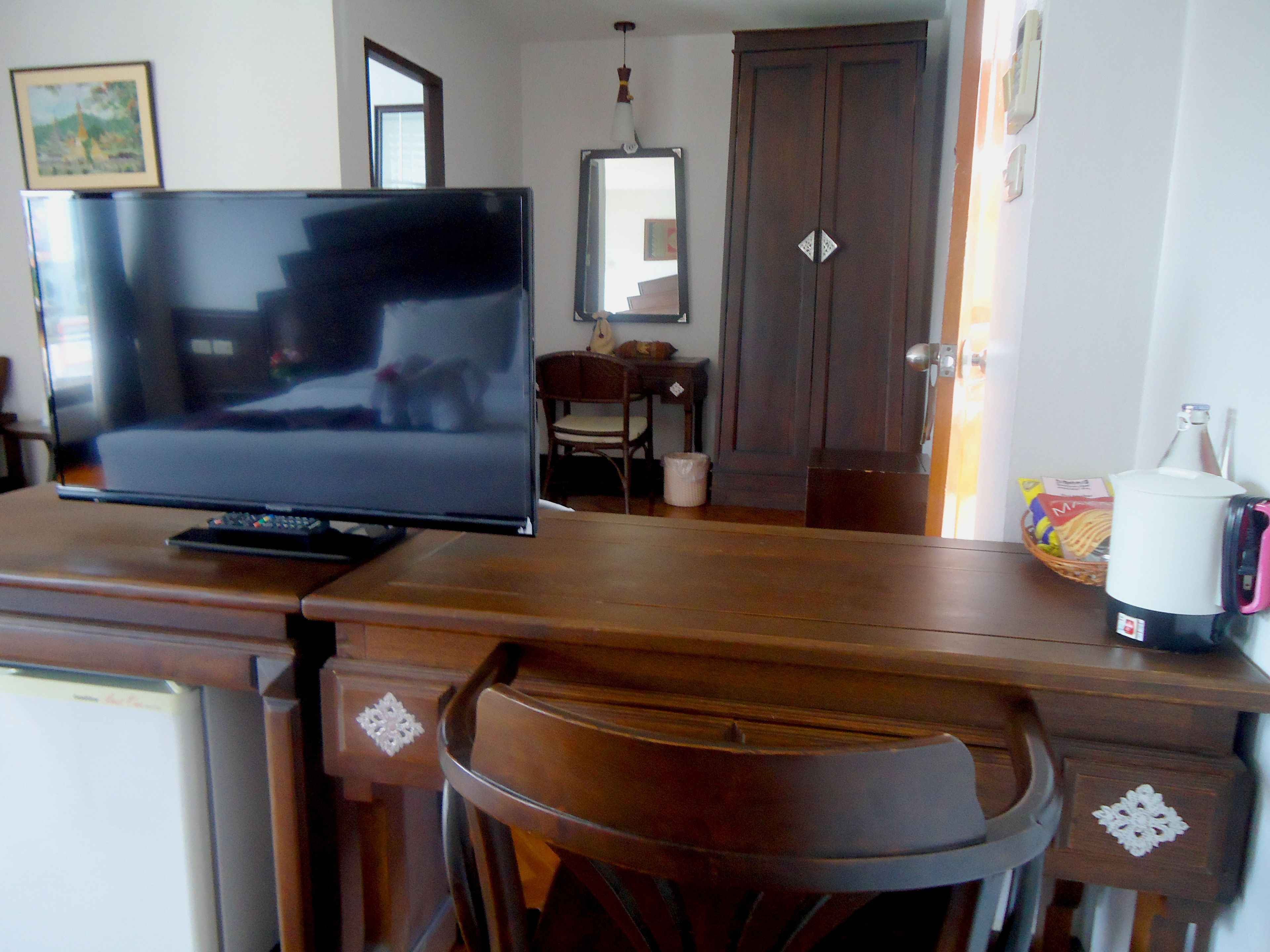 Una scrivania in legno con una TV a schermo piatto, una macchina per il caffè e un cesto di snack.
