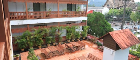 Un edificio de varios pisos con un patio que cuenta con asientos al aire libre, plantas en macetas y una pequeña piscina.