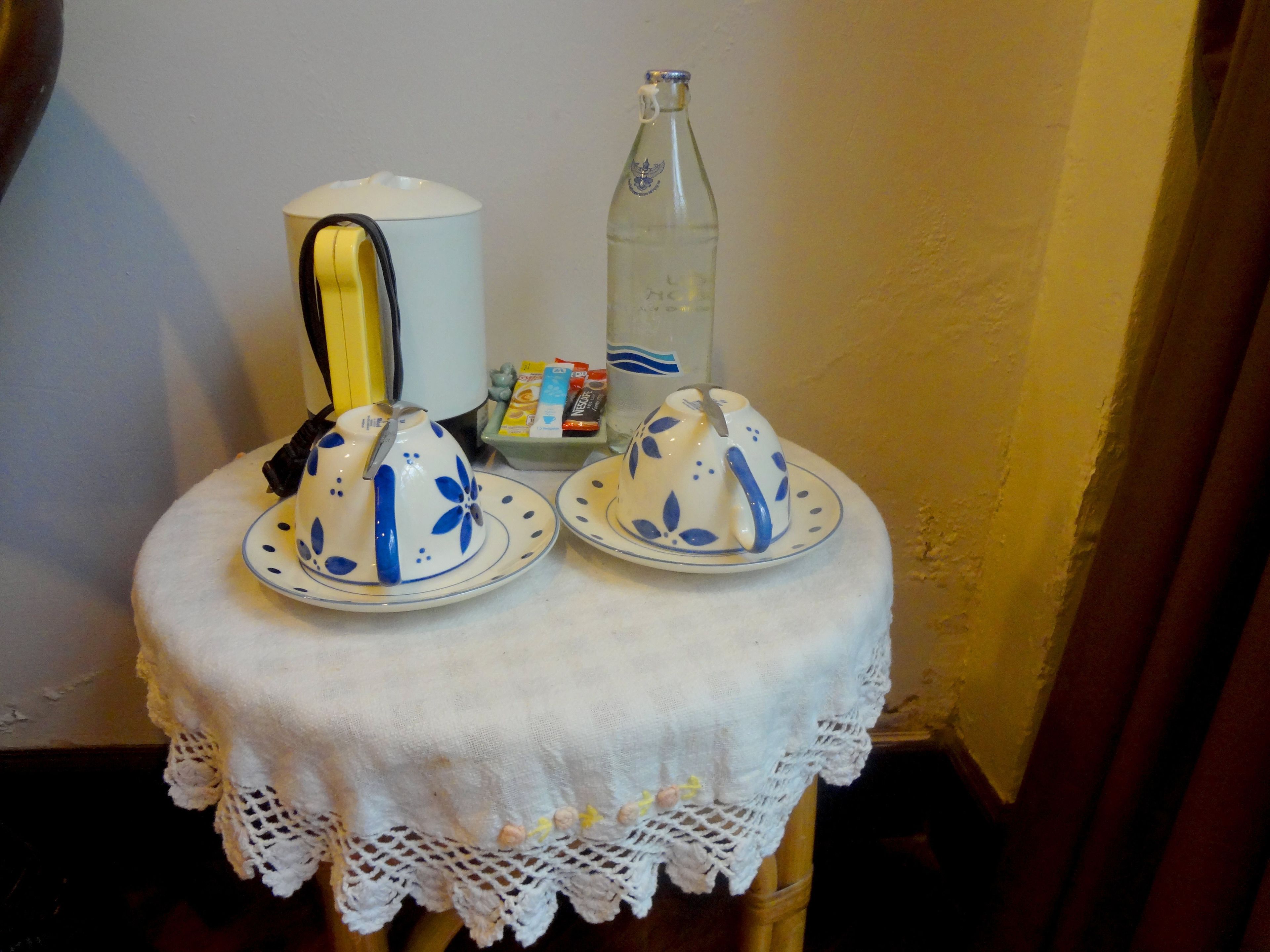 A table with two teapots, a bottle, and some snacks.