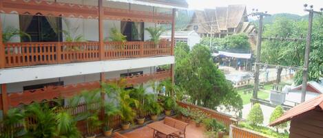 A multi-story building with a balcony, potted plants, and outdoor seating.