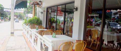 Un restaurant doté d’une terrasse, avec des tables et des chaises en osier.