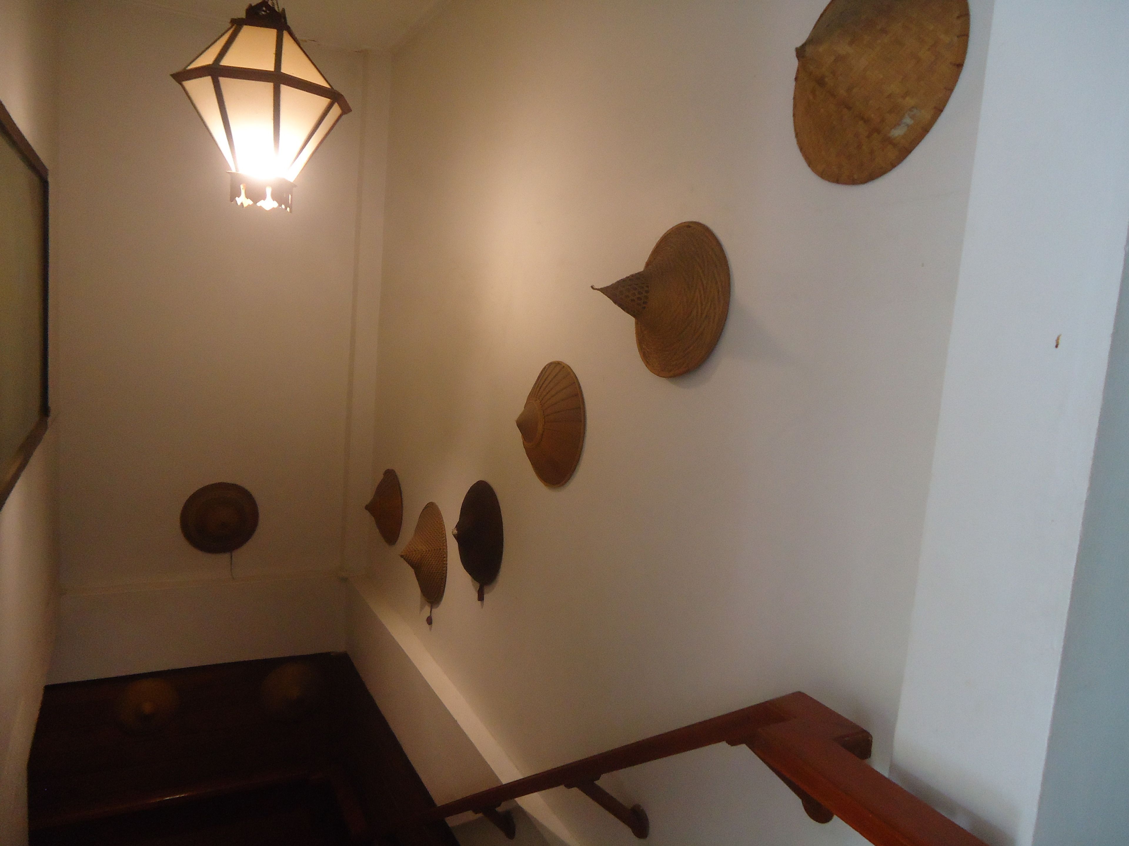 Una escalera con barandilla de madera y un muro adornado con diversos objetos de madera.