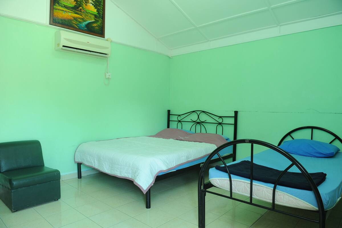 Une chambre avec deux lits, une chaise et un appareil de climatisation fixé au mur.