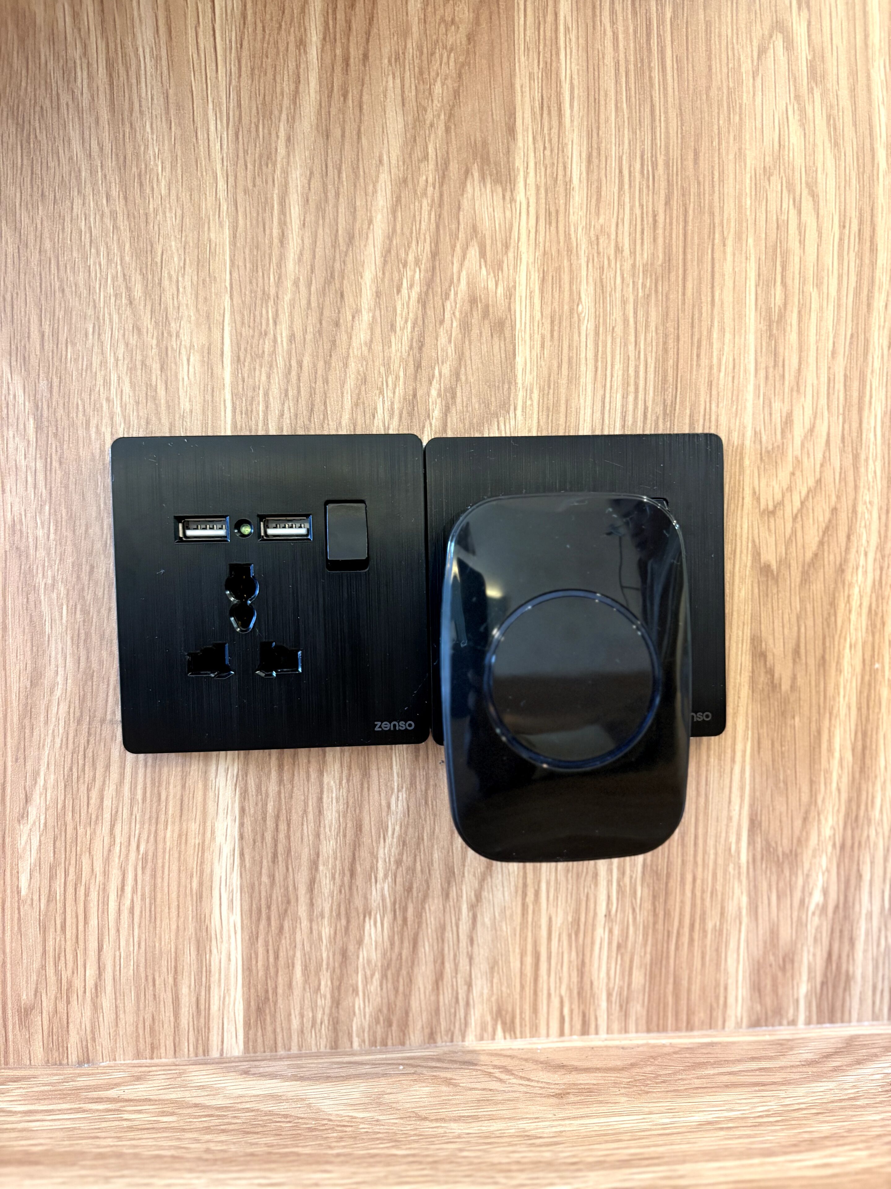 Un dispositivo electrónico negro con puertos USB y un botón de encendido sobre una superficie de madera.