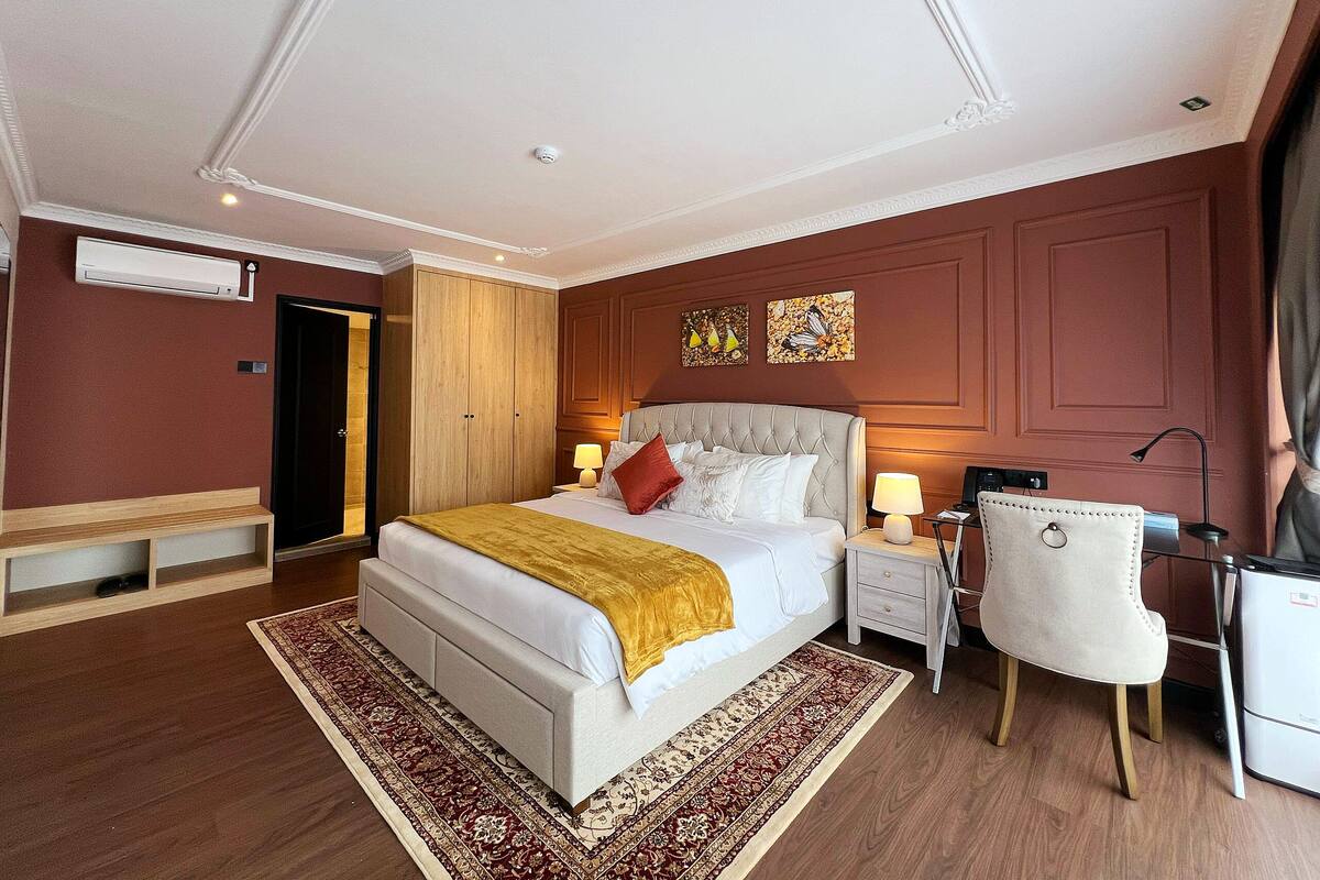 A hotel room with a large bed, bedside tables, a desk, and a chair.