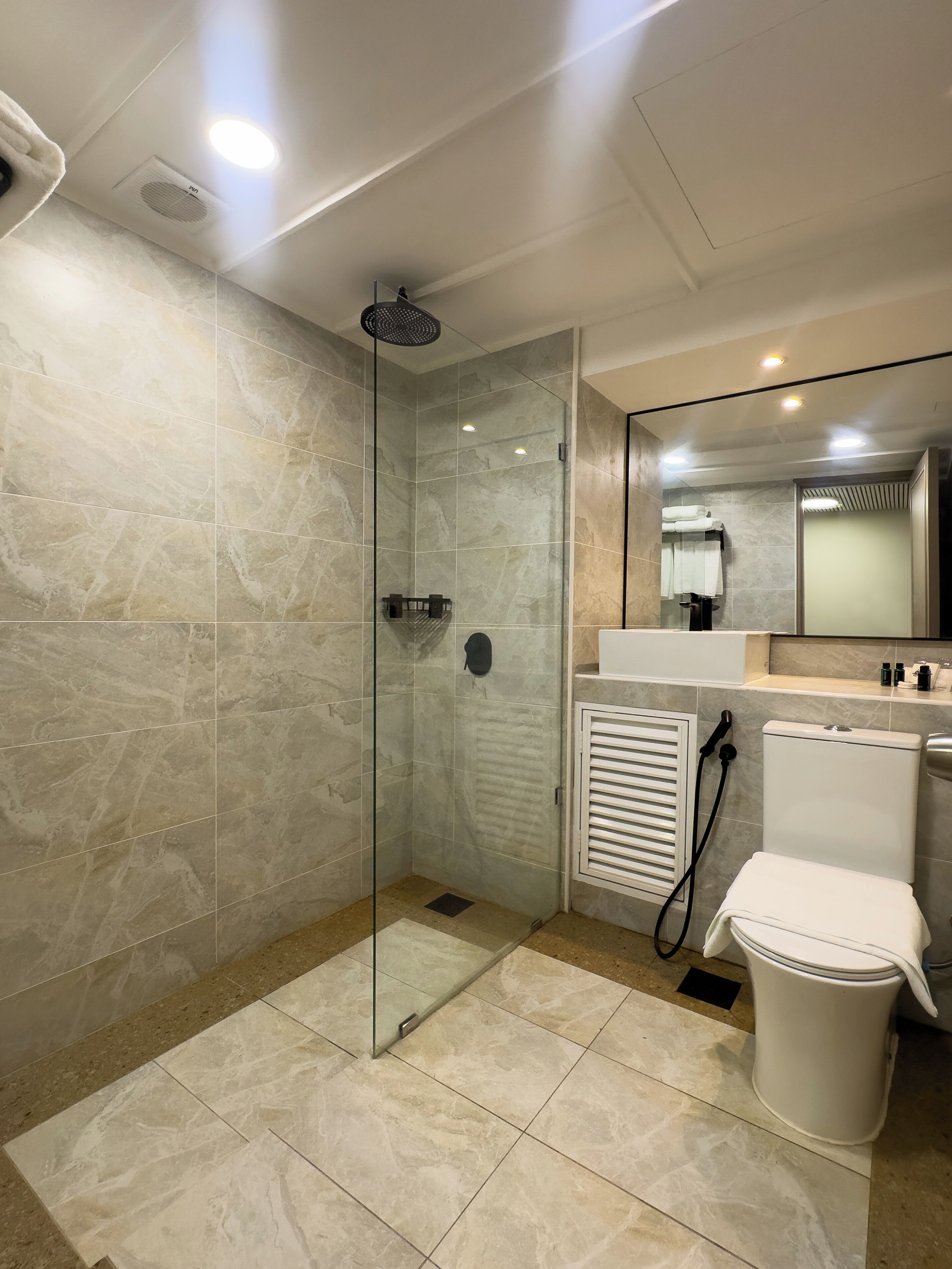 Une salle de bain moderne avec une douche à parois de verre, des toilettes blanches et un meuble-lavabo avec un miroir.