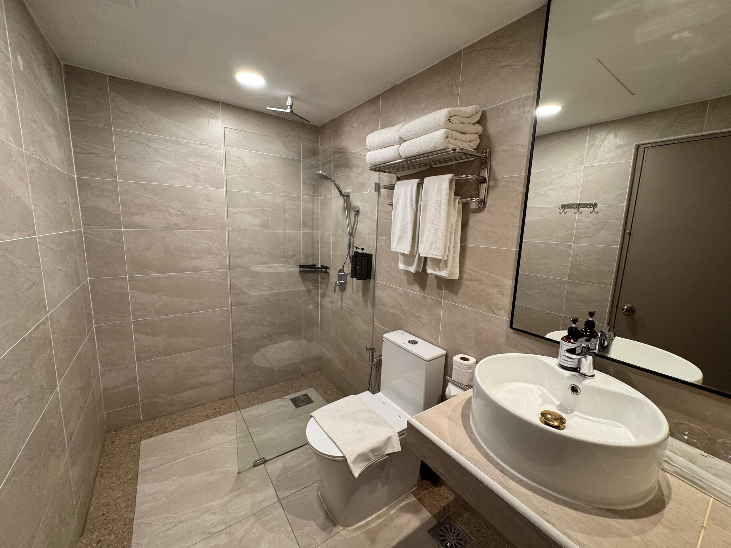Un baño moderno con cabina de ducha, inodoro y un lavabo grande con espejo.