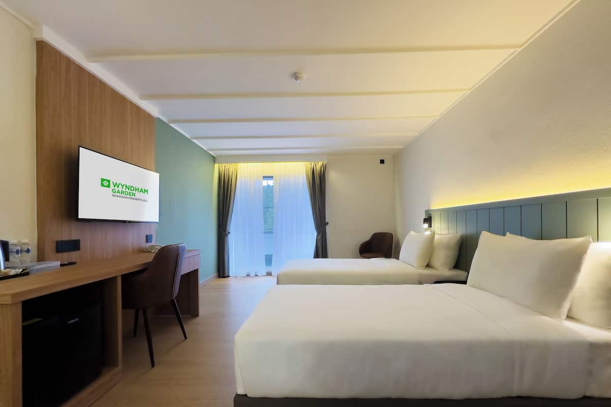 A hotel room with a bed, a desk, a chair, a television, and a window with curtains.