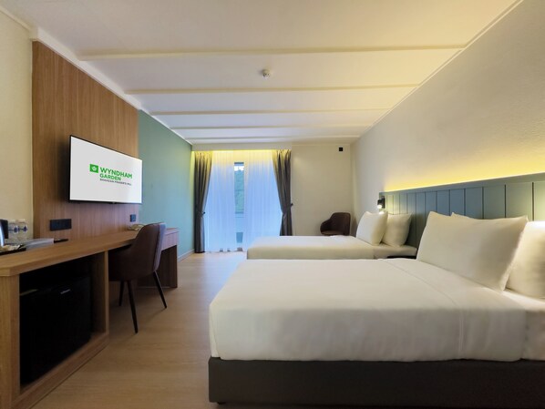 A hotel room with a bed, a desk, a chair, a television, and a window with curtains. - Wyndham Garden Shahzan Fraser's Hill (Raub)