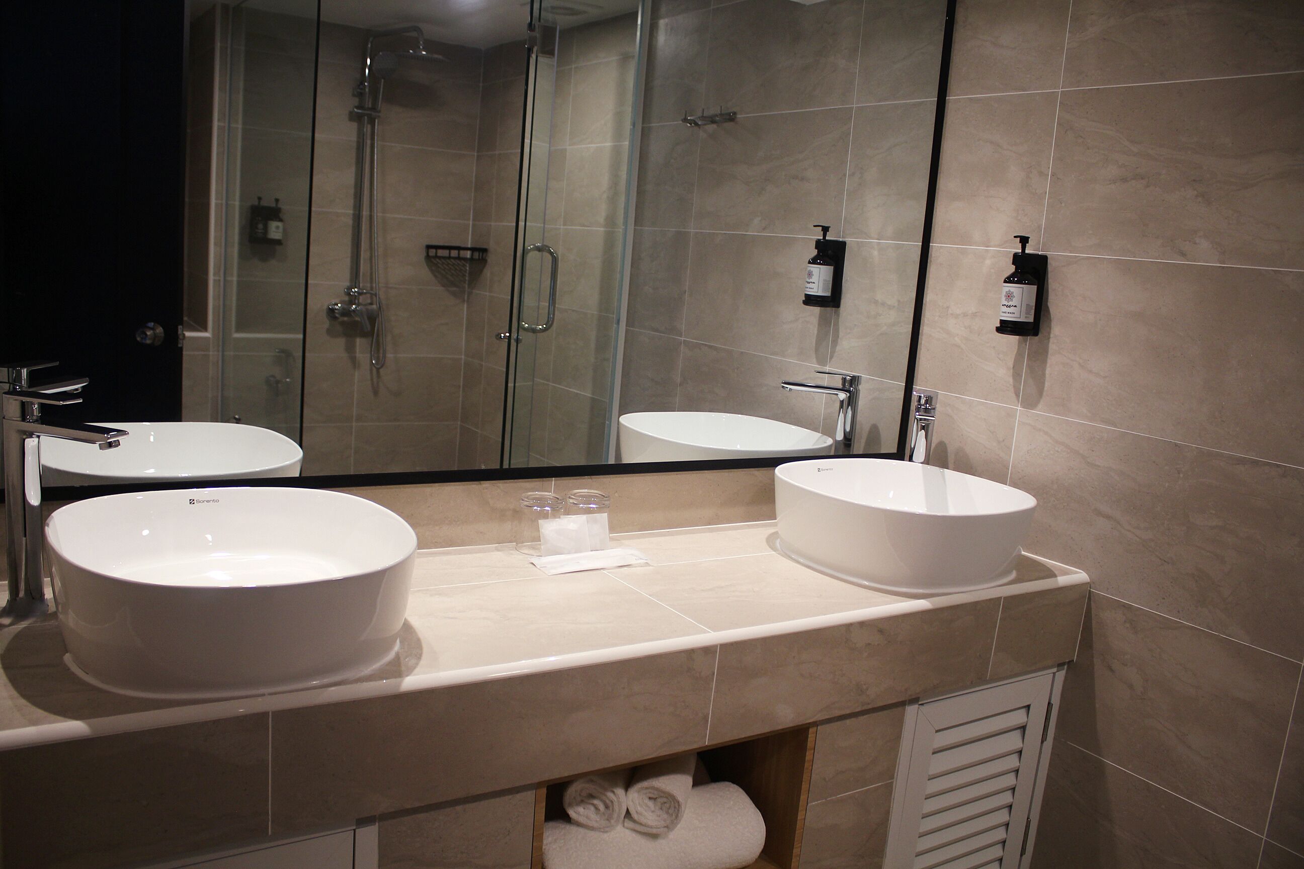 A bathroom with two sinks, a glass shower enclosure, and a mirror.
