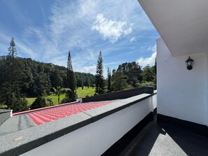 A balcony with a red roof, overlooking a green landscape with trees and a clear sky. - Wyndham Garden Shahzan Fraser's Hill (Raub)
