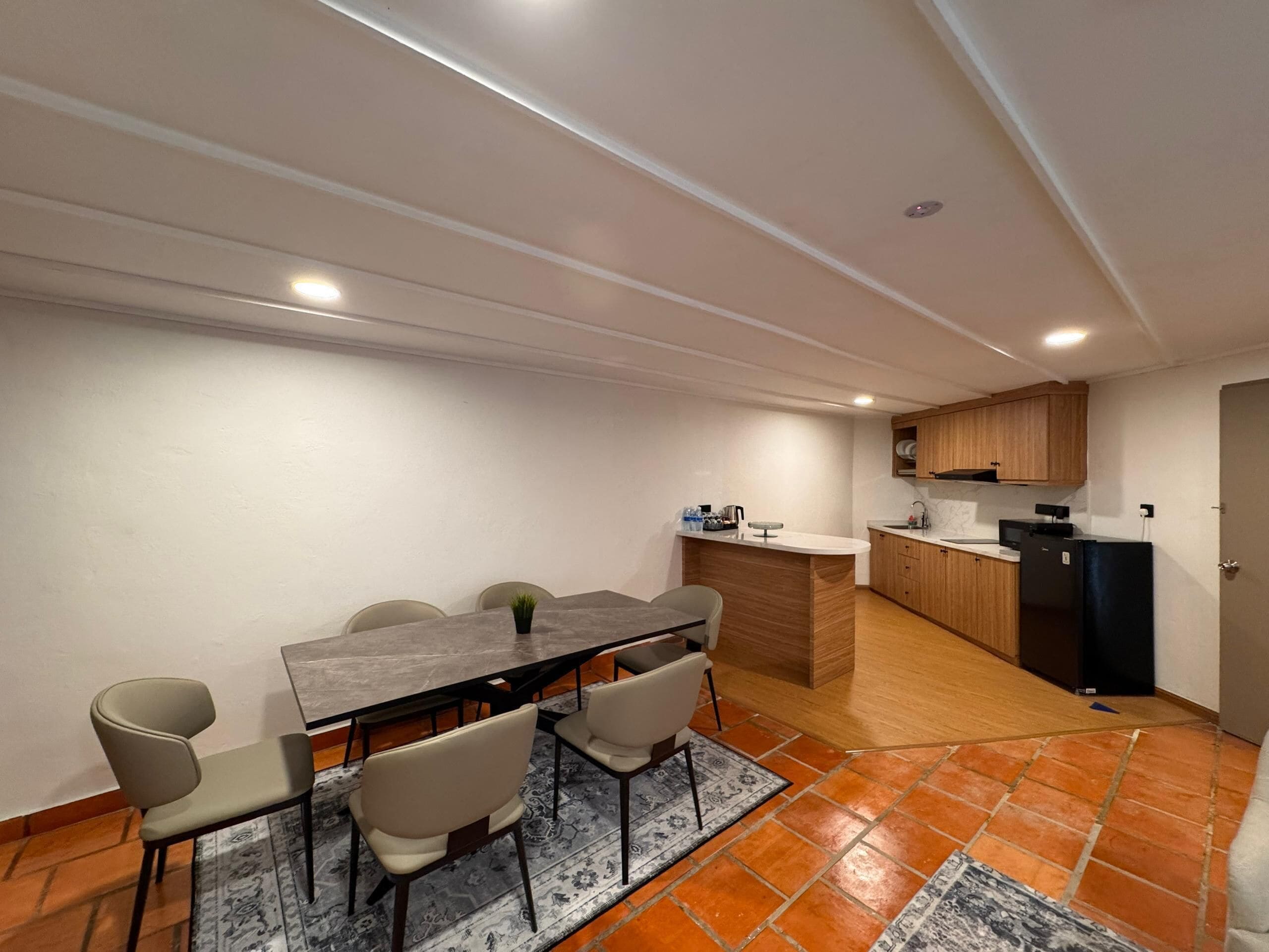 A compact kitchen with wooden cabinets, a built-in island, and a dining area with a table and chairs.