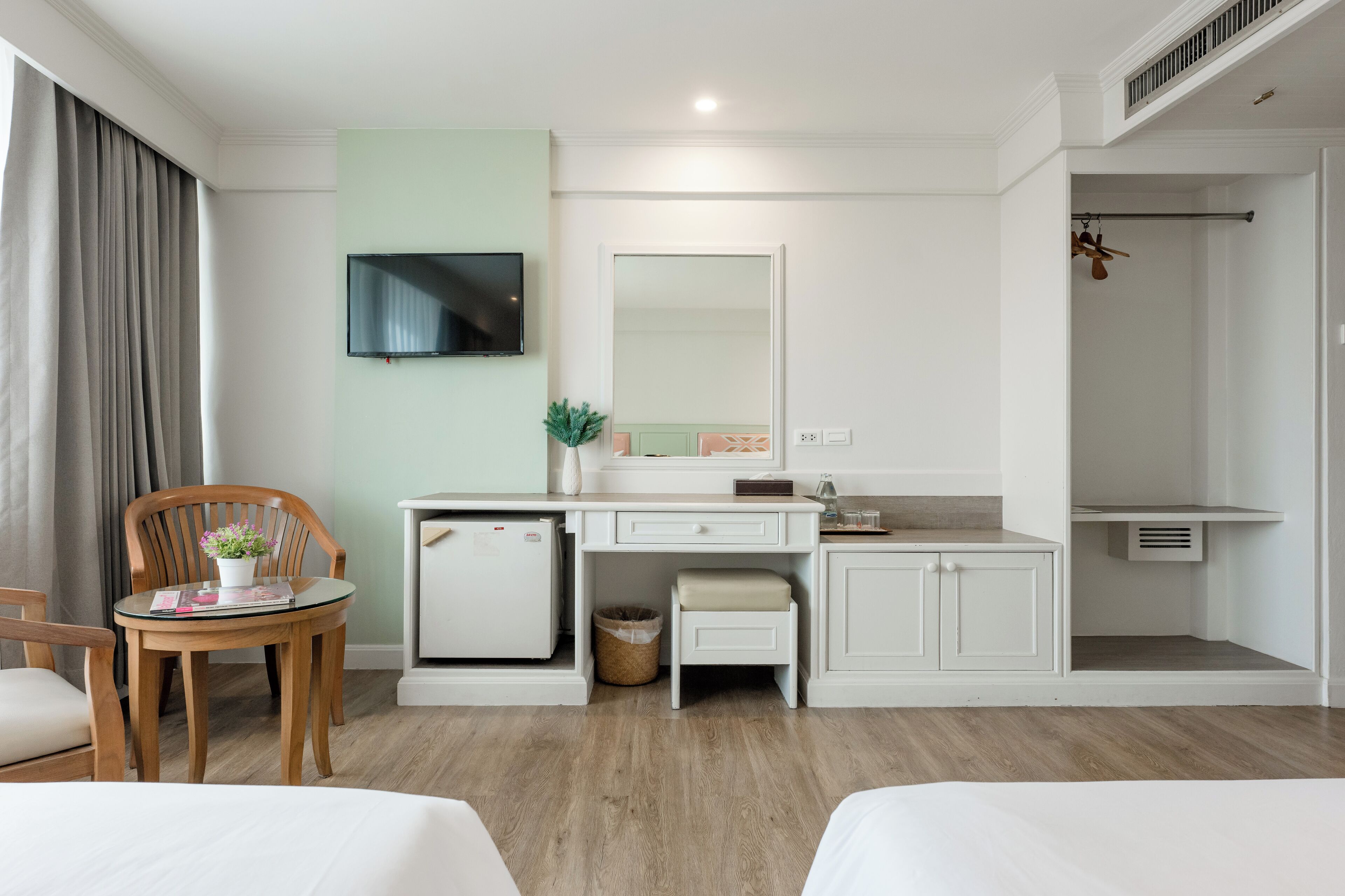 Habitación de hotel con cama, escritorio con computadora, televisor, ducha y una pequeña zona de estar.