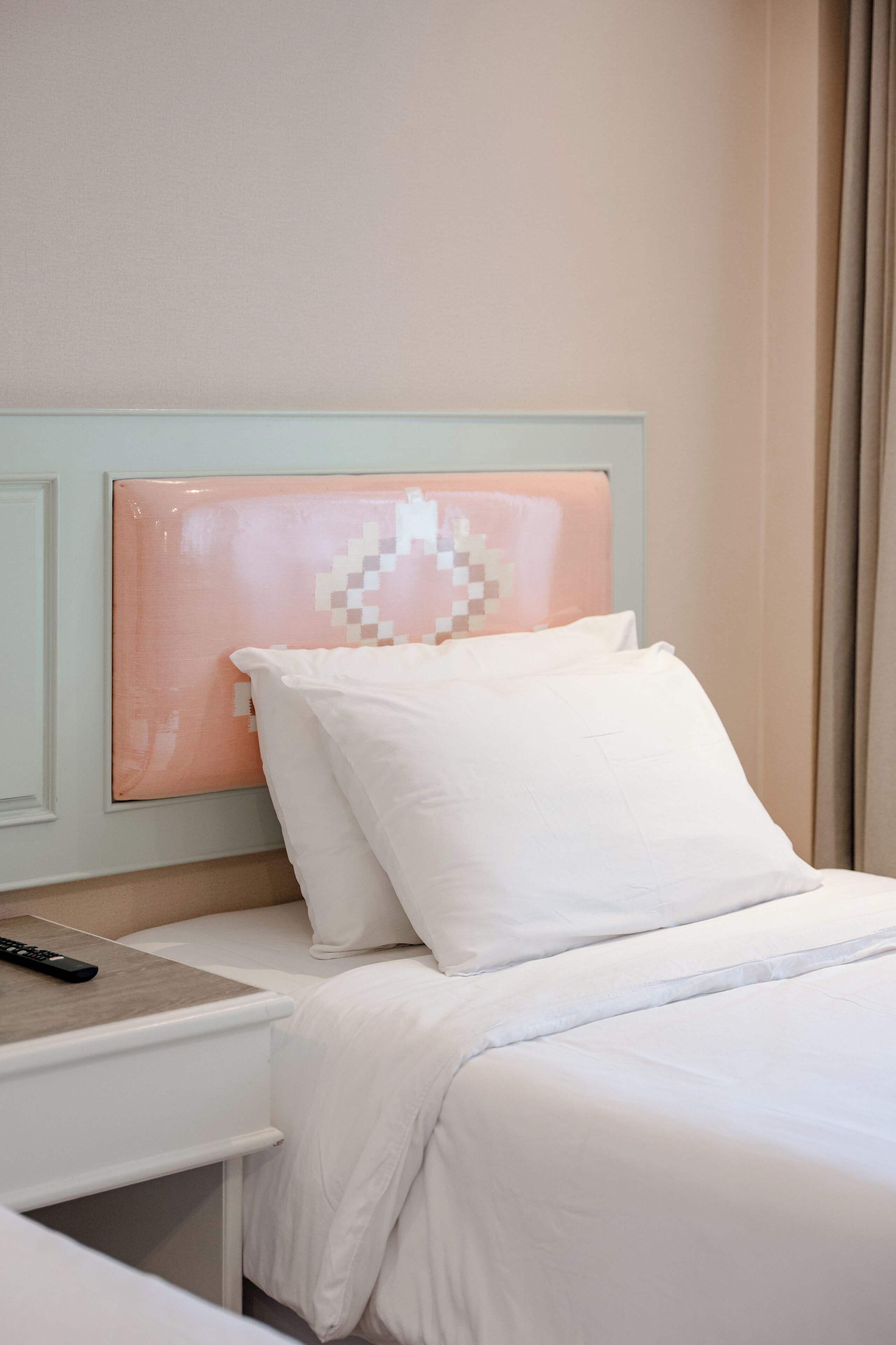 Una cama bien hecha con sábanas blancas y una obra de arte pixelada en la cabecera.