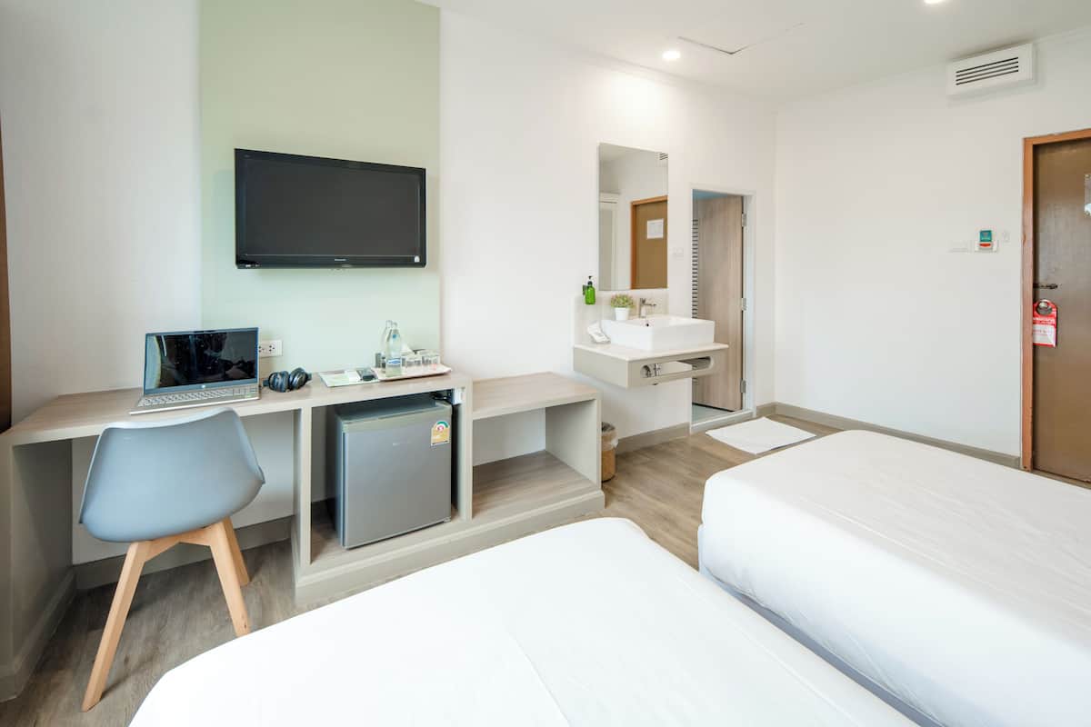 Ein Hotelzimmer mit Schreibtisch, Stuhl, Bett, Fernseher, Waschbecken und Spiegel.