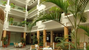 A multi-level hotel atrium with a central open space, multiple floors, and balconies with plants. - Dhevaraj Hotel (Nan)