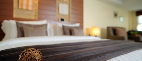 A hotel room with a neatly made bed, a decorative woven ball on the bed, and a view of the room's interior including a window and a wall with a striped pattern.