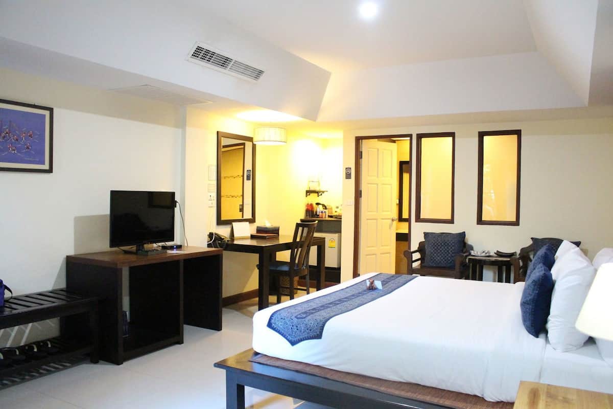 A hotel room with a bed, desk, TV, and a dining area.