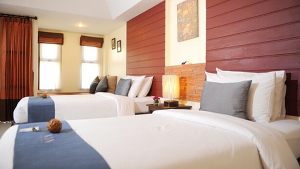 Habitación de hotel con dos camas, una pared decorativa de ladrillo y un ventanal con cortinas.