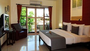 Habitación de hotel con cama, escritorio con silla, televisión y balcón con vistas a zonas verdes.