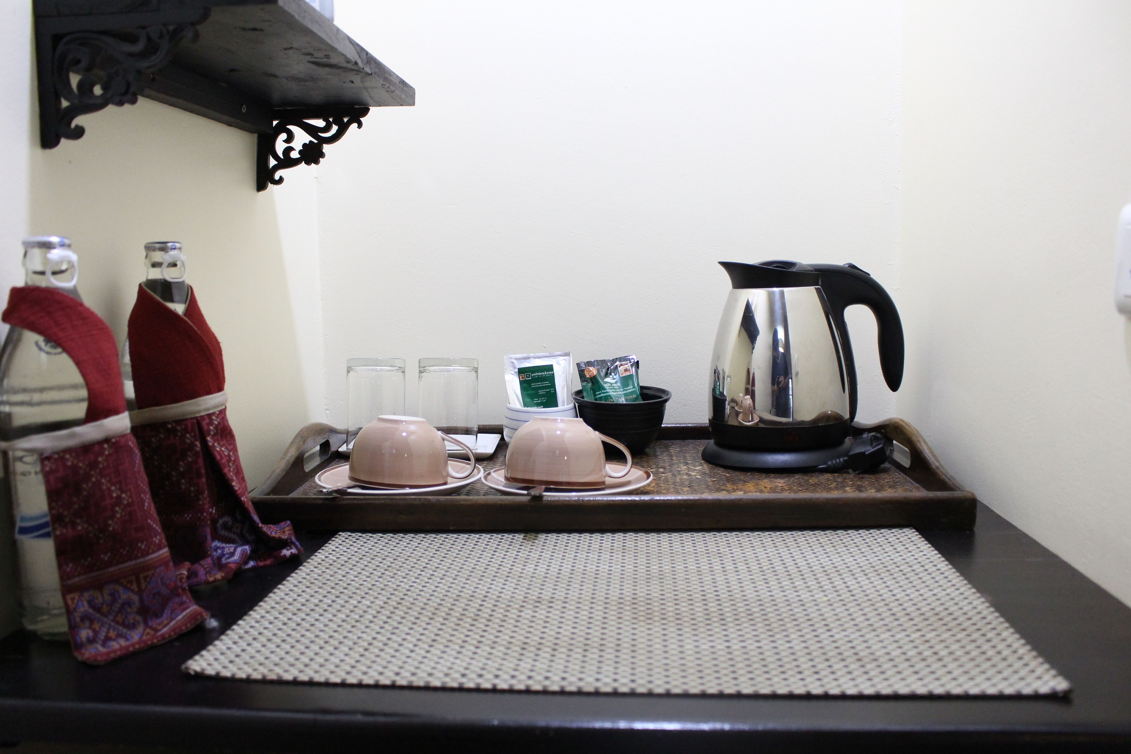 Una encimera de cocina con una tetera, teteras, tazas y una bandeja.