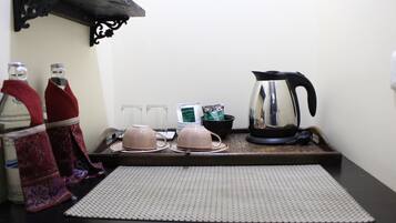 Una encimera de cocina con una tetera, teteras, tazas y una bandeja.