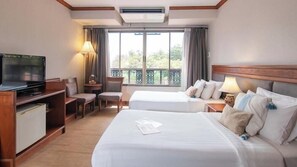 Habitación de hotel con dos camas, televisión, escritorio con lámpara y balcón con cortinas.
