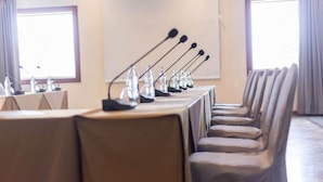 Un salón de conferencias con una larga mesa, varios micrófonos y sillas.