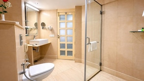 A modern bathroom with a glass-enclosed shower, a white toilet, a sink with a mirror, and a vanity with a telephone.