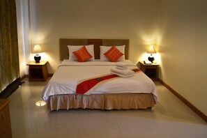 Una habitación de hotel con una cama grande, dos mesitas de noche y dos lámparas.