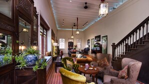 A spacious lobby with a high ceiling, ornate wooden furniture, and a staircase leading to upper floors. - Muntri Mews (George Town)