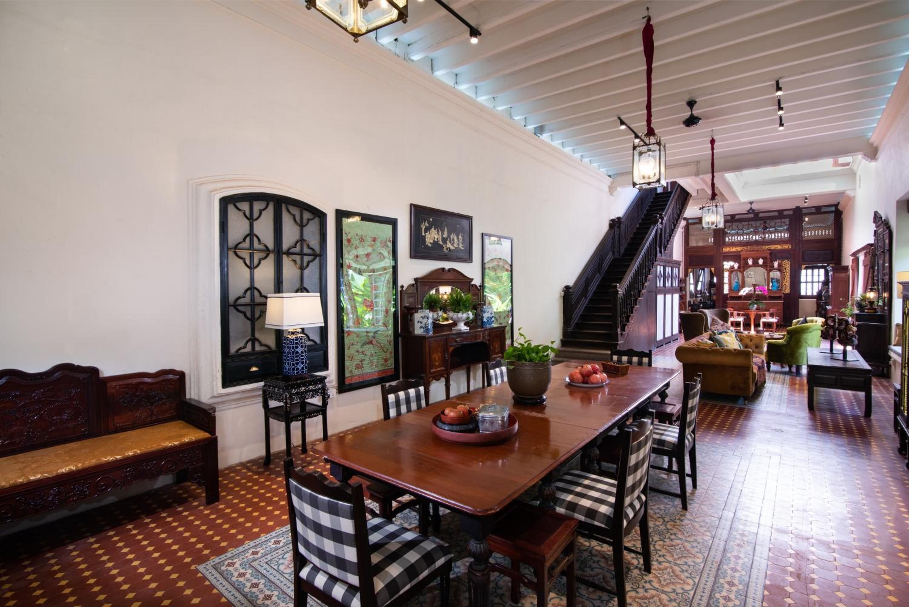 A spacious dining area with a long wooden table, surrounded by chairs, and a staircase leading to an upper level.