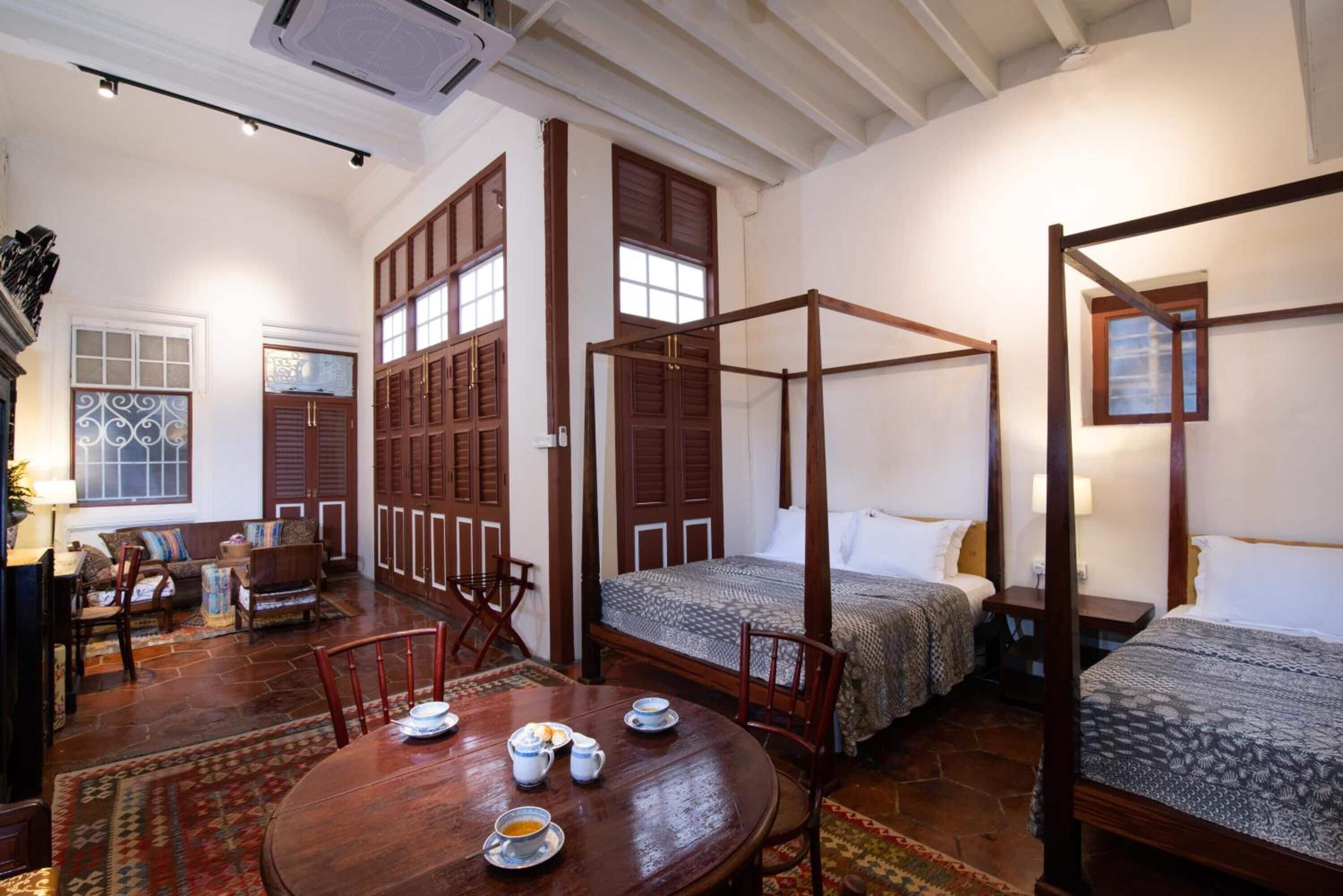 A traditional room with a four-poster bed, a dining table with chairs, and a sofa.