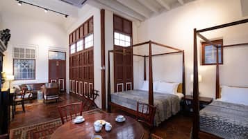 A traditional room with a four-poster bed, a dining table with chairs, and a sofa.