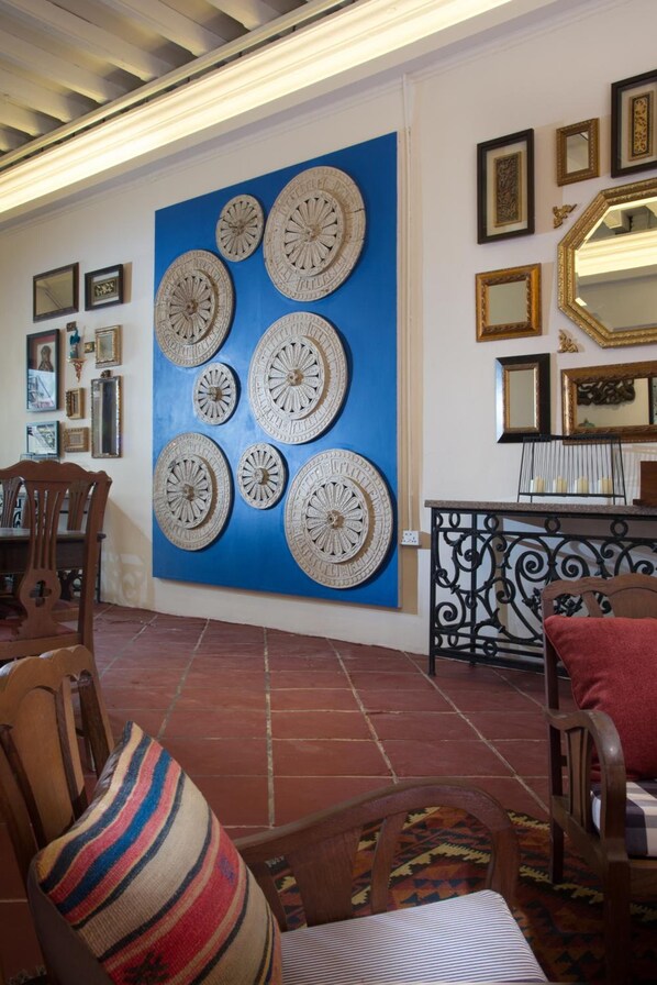 A room with a blue wall decorated with circular wall art, a black wrought iron console table, and several framed pictures.