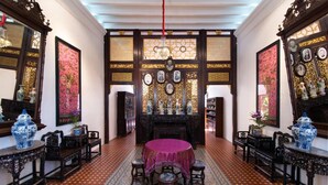 A traditional room with a central round table, ornate wooden furniture, and patterned floor tiles. - Muntri Mews (George Town)