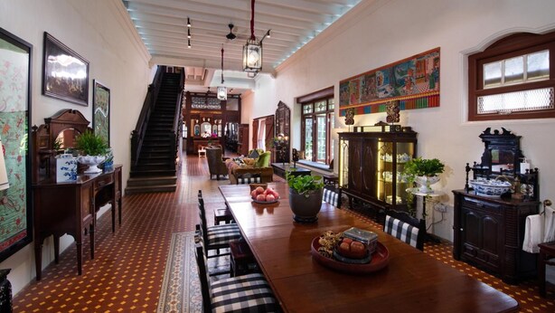 A spacious dining area with a long wooden table, benches, and a staircase leading to another level. - Muntri Mews (George Town)