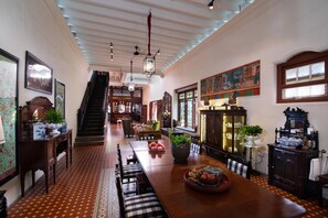 A spacious dining area with a long wooden table, benches, and a staircase leading to another level.