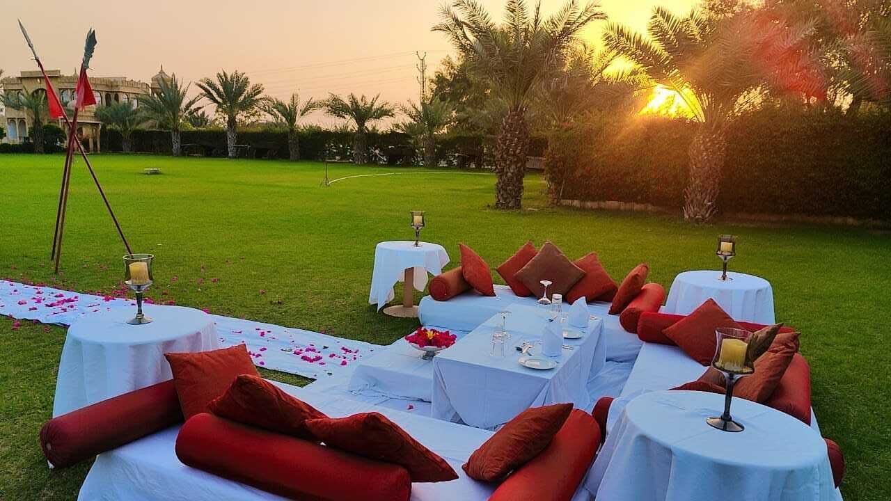 An outdoor dining setup with round tables, red cushions, and a white tablecloth.