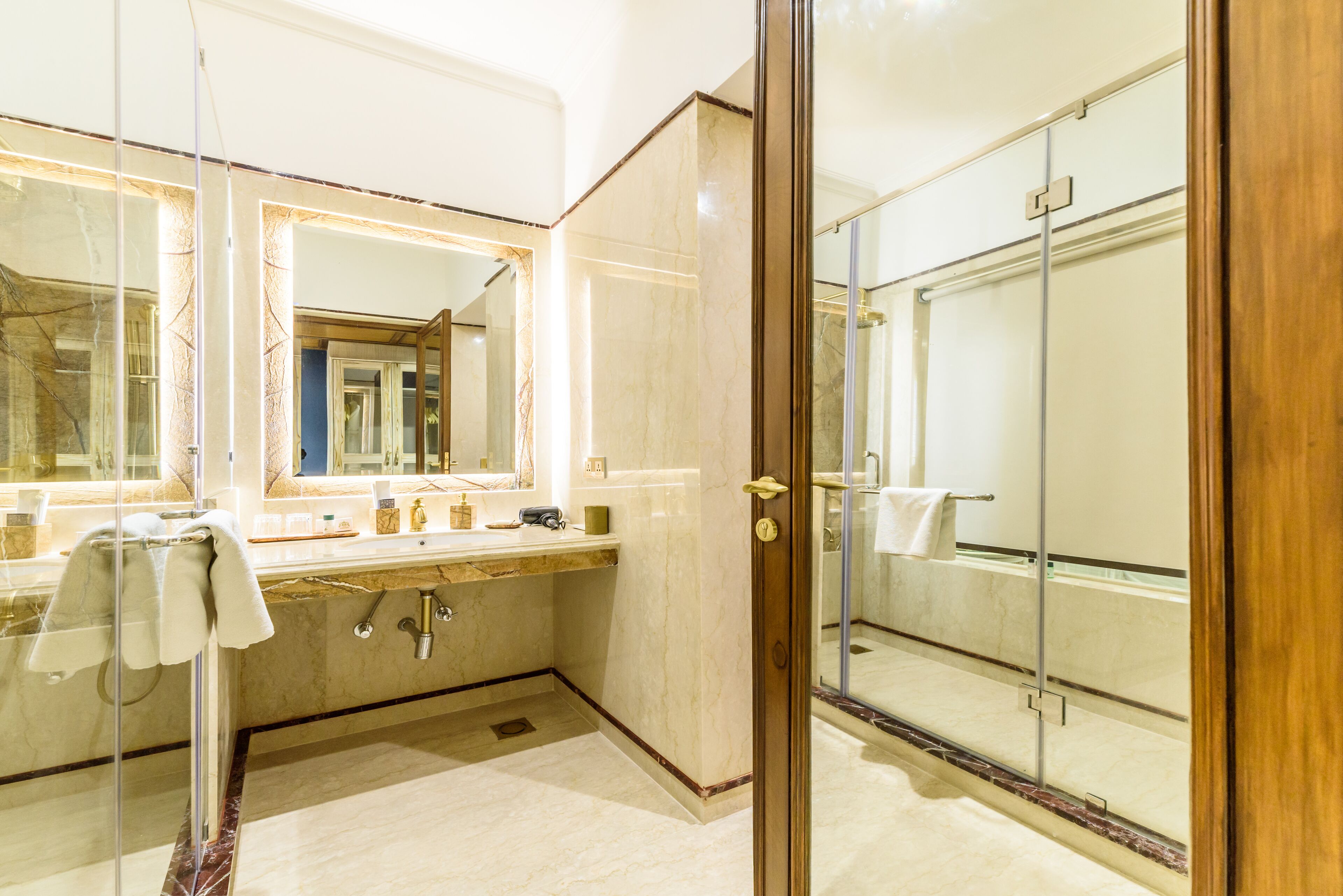 Un baño moderno con cabina de ducha de vidrio, tocador de mármol y un espejo grande.