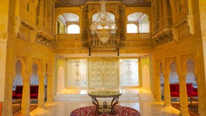 Un salón imponente con arcos decorativos, un candelabro y una mesa central.