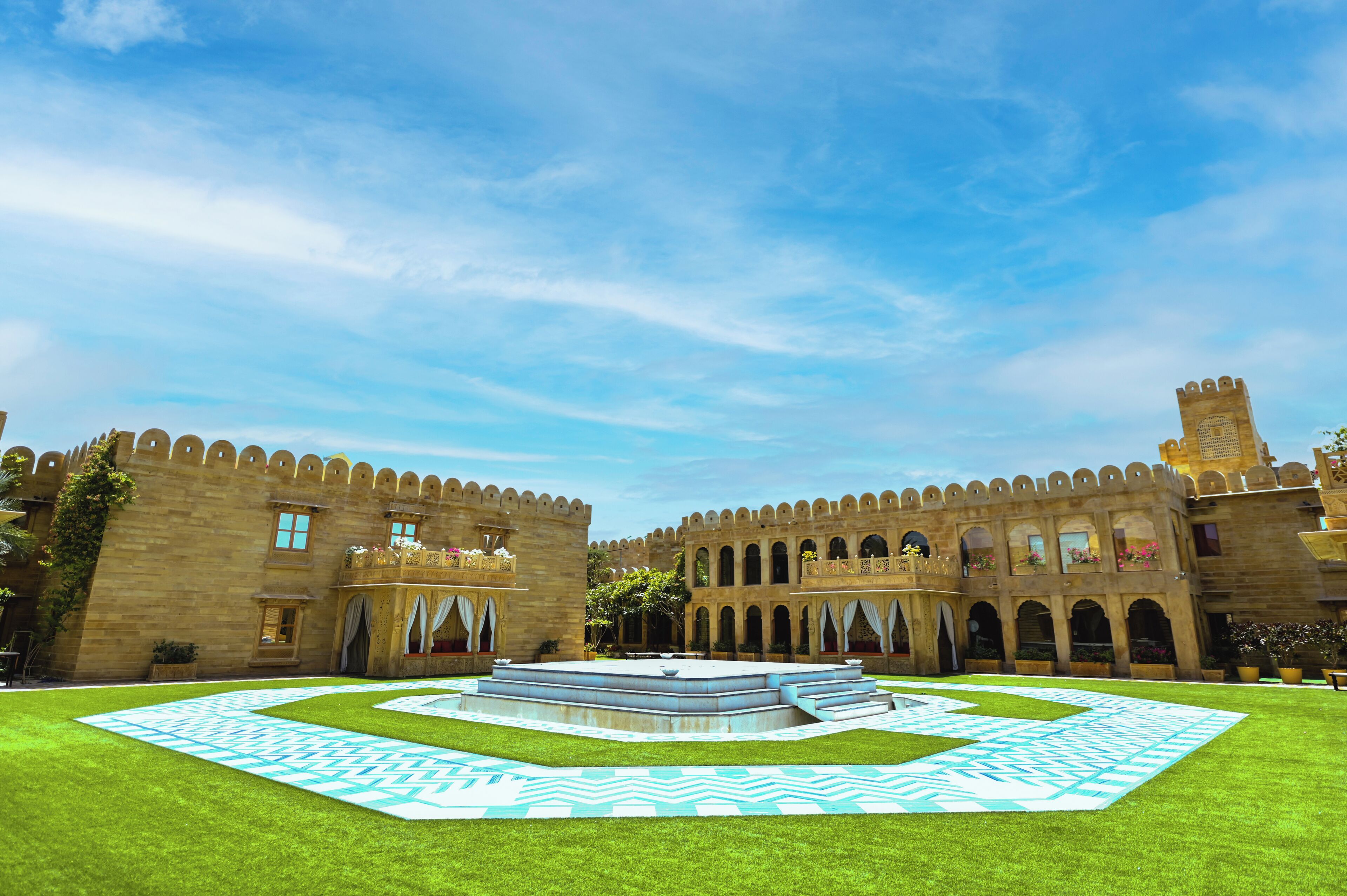 A courtyard with a central fountain, surrounded by a stone building with arched windows and balconies.