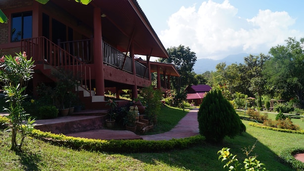 A two-story building with a balcony, surrounded by well-maintained gardens and a clear sky. - Ban Rai Tin Thai Ngarm Eco Lodge (Mae Rim)
