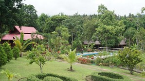 A lush garden with manicured lawns, a swimming pool, and a red-roofed building. - Ban Rai Tin Thai Ngarm Eco Lodge (Mae Rim)