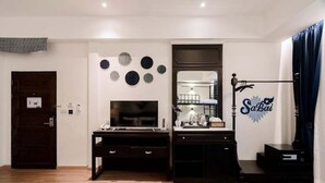 Een moderne woonkamer met een donker houten bureau, een flatscreen televisie, een spiegel en een decoratieve wand met cirkelvormige patronen.